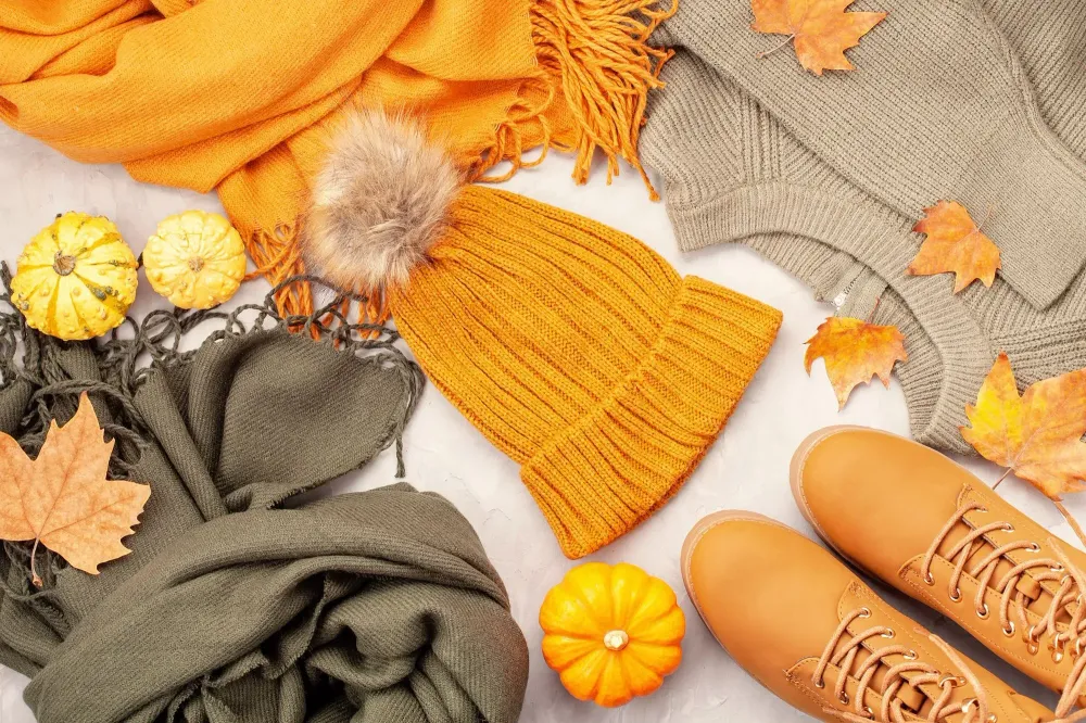 Flat lay with fall clothes, shoes, pumpkins, and leaves
